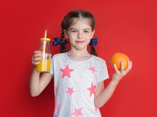 cute girl holding a glass of juice and orange, concept of a children's vegetarian and healthy eating