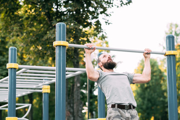 sport fitness and outdoor training. man doing pull ups on bar. chest muscles and biceps workout.