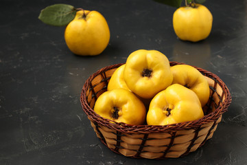 Ripe yellow quince fruit on dark background in a wicker basket, healthy lifestyle, nutrition Copy space