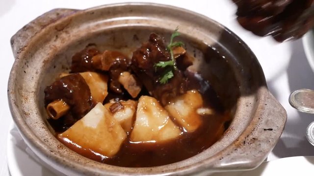 Motion of people eating stewed oxtail and radish inside small pot at Chinese restaurant with 4k resolution.