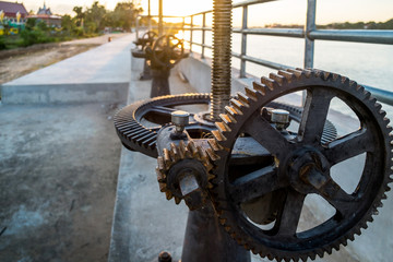 3 black gears of the floodgate in evening sun.