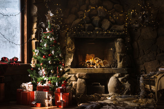 Christmas decorated fireplace and gifts in cozy chalet. Fire in stone fireplace