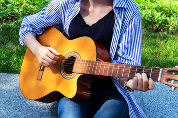 The girl plays the guitar chords on the guitar.