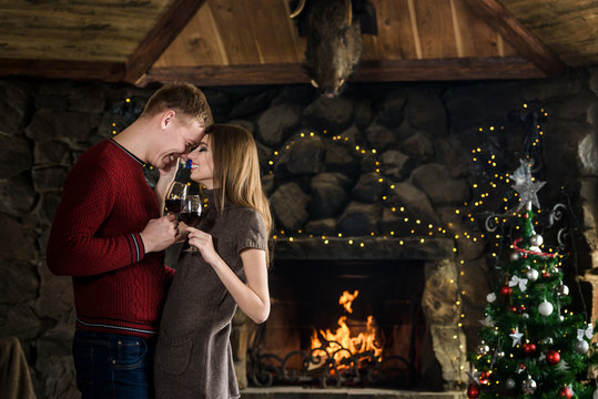 Happy couple with glasses near fireplace