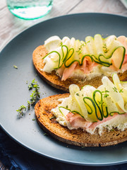 Rye bread toasts with fresh cheese, ham and cucumber slices. Bright healthy sandwiches for breakfast, brunch