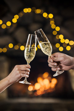Toasting and celebration champagne glasses on bokeh garlands background. Vertical