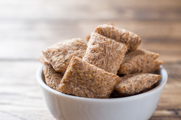 Cookies crackers square shape in a plate on a wooden table.