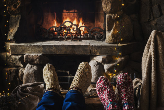 Feets in woolen knitted socks near fireplace