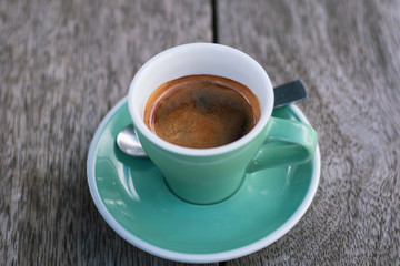 Black coffee in a green cup on a wooden table