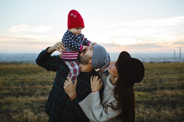 The dad holds his face in his arms with his mother. Photo session with family at sunset.