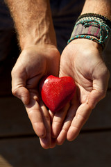 Mani di uomo che porgono un cuore.