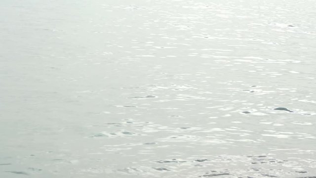 Mirrored surface of splashing sea water at sandy beach during sunset time. Beautiful nature silver color saltwater background. Turkey. Real time 4k video footage.