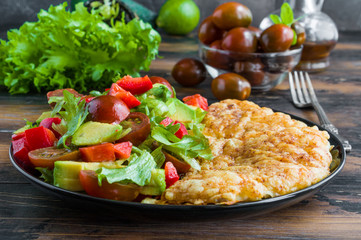 Tilapia fish fillet baked with grated cheese and paprika topping and vegetable salad. Blake plate, wooden table.