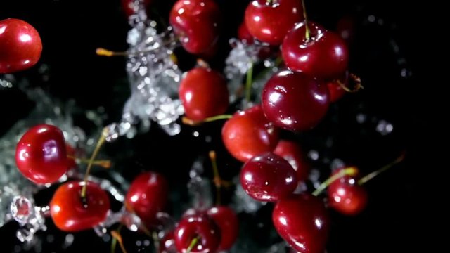 Cherry with water bouncing against to the camera on a black background in slow motion