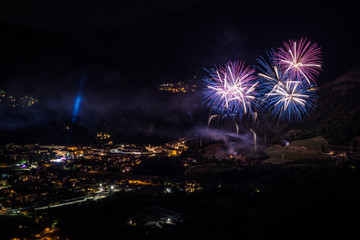 celebration with fireworks upon a mountain with town at night