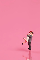 Fototapeta na wymiar Miniature people: a couple standing on pink background idea for love concept