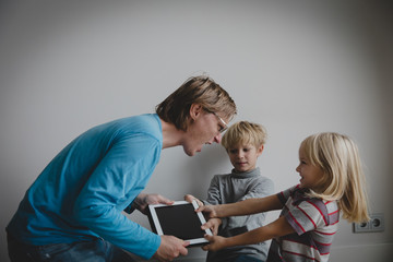 computer addiction- father taking touch pad from angry kids