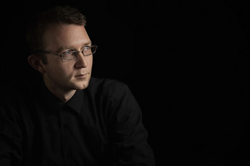 Fototapeta premium young man close up portrait, on black background with glasses
