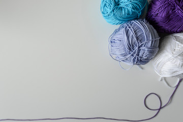 Colorful yarn balls in the corner of image, and a thread as a bottom frame with copy space on white...