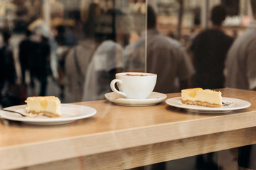 View through the glass. A cup of coffee and cheesecakes on the table. Concept take a break or rest during the day.