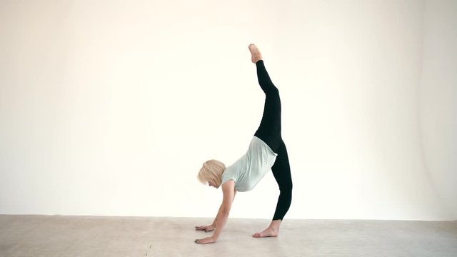 Caucasian blond model size plus practice yoga asana at white background slow motion