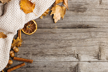 Leaves, knitted blanket, dry orange, cinnamon and acorns on an old wooden table, copy Space, Fall.