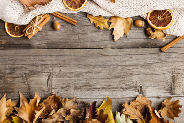 Leaves, knitted blanket, dry orange, cinnamon and acorns on an old wooden table, copy Space, Fall.