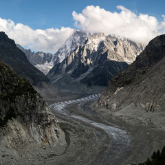Meandering galcier Mer de Glace Chamonix and Aguille du Tacul with cloud layer and blue sky