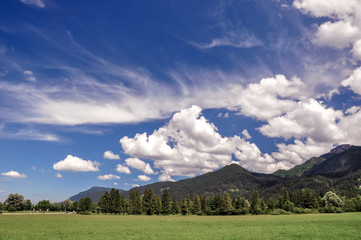 Typical bavarian landscape, Alps, south Bavaria, Germany. Beautiful mountains, hills and peaceful meadows, blue sky with some clouds, sunny spring or summer day.