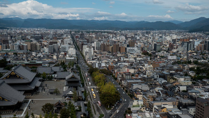 Aerial shots of the city of Kyoto. Skyscrapers and buildings expand out into the distance of the Japanese city as a stormy sky and clouds form over the cityscape.