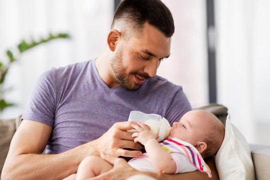 Family, Parenthood And People Concept - Father Feeding Little Daughter With Baby Formula From Bottle At Home