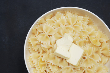 Top view of Farfalle Pasta in Bowl with Butter Close Up over Dark Background with copy space.