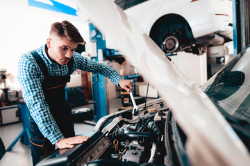 Young Auto Mechanic Repairs Car With A Wrench.