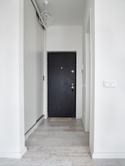 Empty hallway with closed door inside an apartment. White corridor inside an apartment block.