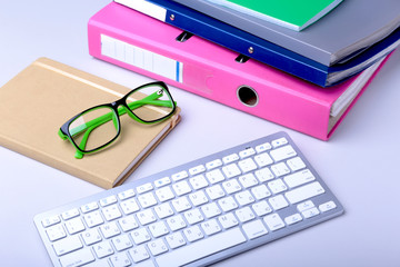 Office desk table with blank notebook, keyboard, other supplies and coffee cup. Top view with copy space