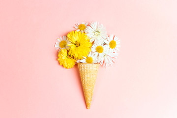 Waffle cone with flowers on pink background.