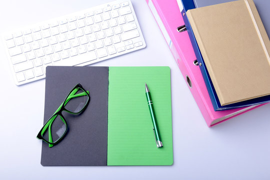 Office desk table with blank notebook, keyboard, other supplies and coffee cup. Top view with copy space