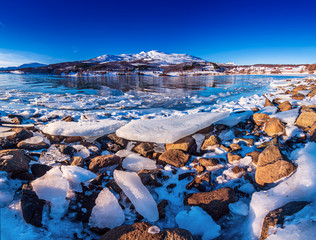 Wide angle view of beautiful winter lake with ice on the coast at Lofoten Islands in Northern Norway