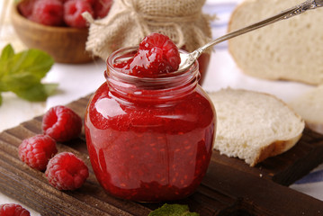 Raspberry jam in a glass jar on the kitchen table.