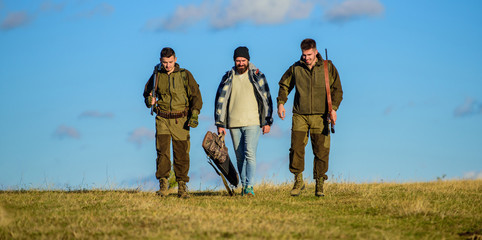 Hunters with guns walk sunny fall day. Brutal hobby. Group men hunters or gamekeepers nature background blue sky. Guys gathered for hunting. Men carry hunting rifles. Hunting as hobby and leisure
