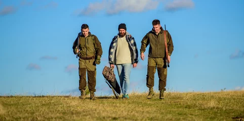 Foto op Plexiglas Jacht Hunters with guns walk sunny fall day. Brutal hobby. Group men hunters or gamekeepers nature background blue sky. Guys gathered for hunting. Men carry hunting rifles. Hunting as hobby and leisure