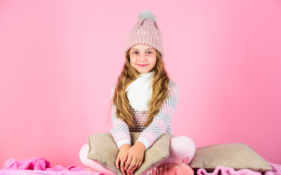 Winter fashion concept. Girl long hair relaxing pink background. Winter fashion for children. Kid smiling fashion model. Kid girl wear cute knitted fashionable hat and comfortable cozy clothes