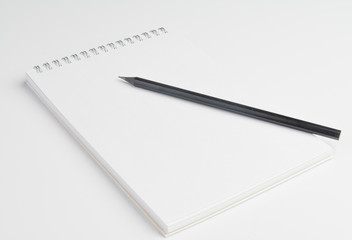 The pencil is on the notebook of the student. Close up.
