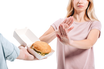 cropped image of woman rejecting unhealthy burger isolated on white