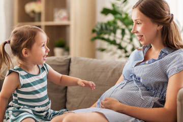 pregnancy, people and family concept - happy pregnant mother and little daughter at home