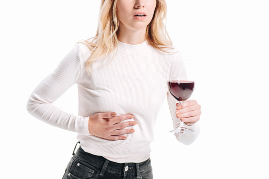 cropped image of woman showing liver pain and holding glass of red wine isolated on white