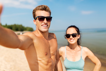 Obraz premium fitness, sport and lifestyle concept - happy couple taking selfie on summer beach