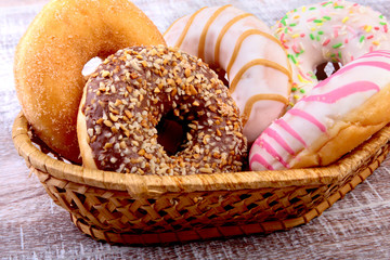Wicker basket with assorted delicious homemade doughnuts in the glaze, colorful sprinkles and nuts....