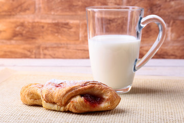 Easter breakfast with traditional hot cross bun with jam and glass with milk. From above on wooden table.