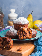 Chocolate home made baked muffins with pears and icing sugar on winter background